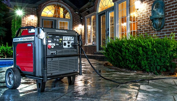 Honda EU7000is inverter generator with power cord on a residential patio for home backup power
